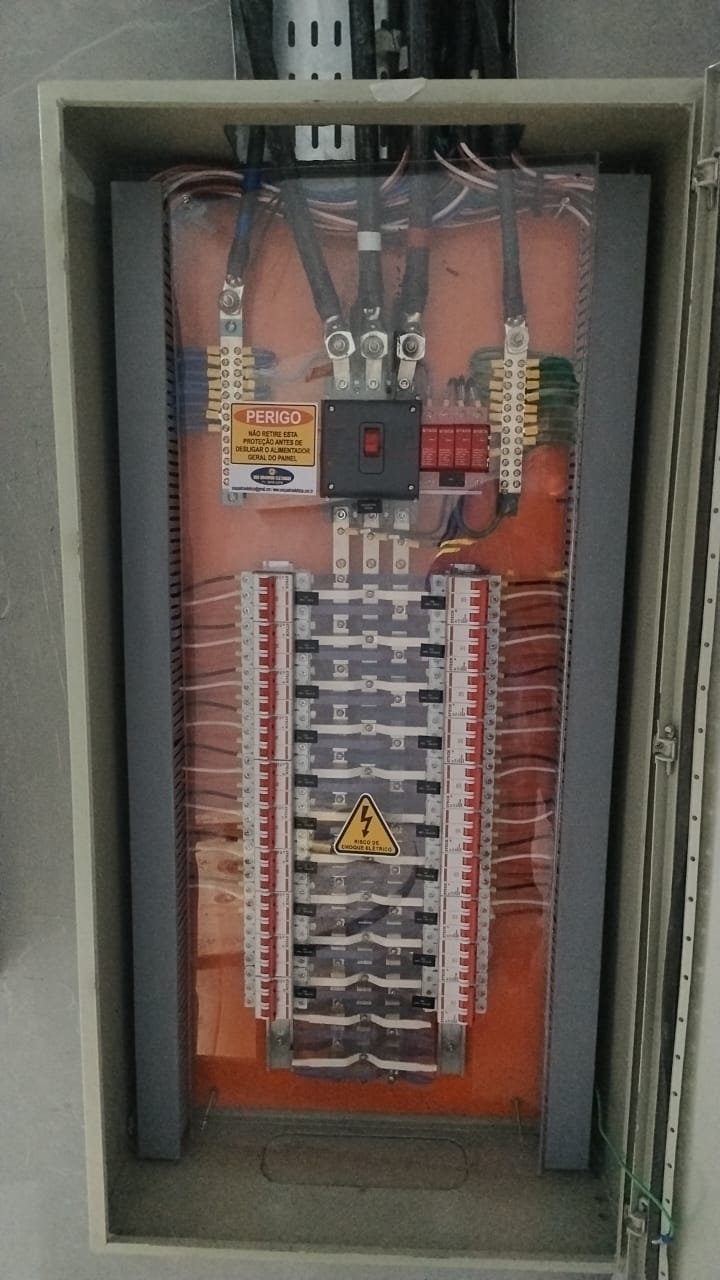 Quadro de distribuição residencial com barramentos e sinalização de segurança de risco de choque
